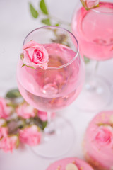Two glasses with pink grape wine with rose flowers. Romantic dinner concept.