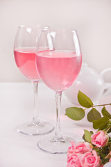 Two glasses with pink grape wine with rose flowers. Romantic dinner concept.