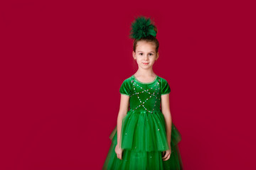 Beautiful little girl princess dancing in luxury green dress isolated on red background. Carnival party with costumes