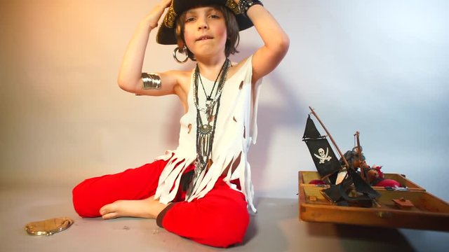 The child puts a pirate hat on his head.