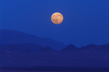 Naklejka na ściany i meble Wonderful full moon rising in the Mojave Desert in California.
