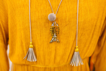 closeup of female sweater on hanger with tassels and locket.