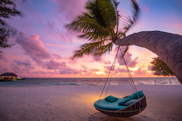 Tropical sunset beach background as summer landscape panorama with beach swing or hammock and white sand and calm sea beach banner. Perfect beach scene vacation or summer holiday concept - obrazy, fototapety, plakaty