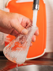A man pours tap water into a glass flask.