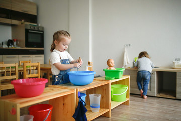 Toddler whips soap suds in basin at Montessori
