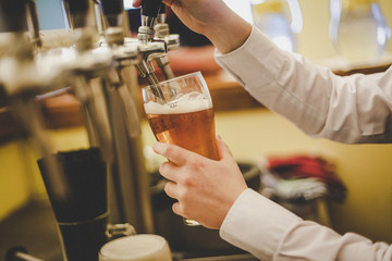 A hand holding a glass of beer