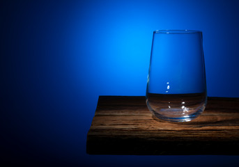 Empty glass goblet standing on a wooden table on a gradient background
