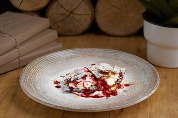 french dessert millefeuille of puff pastry and custard and ice cream on a plate and on a wooden...