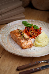 Baked salmon, grilled with mashed potatoes and salad on a wooden background