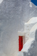 An old Mediterranean architecture Greek church wall with a red wooden window at the front, in Mykonos, Cyclades, Greece