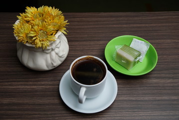 a cup of brewed black coffee and a piece of layer cake.