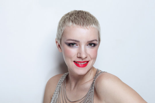 Vintage style portrait of young smiling woman with short blonde hair and fancy makeup