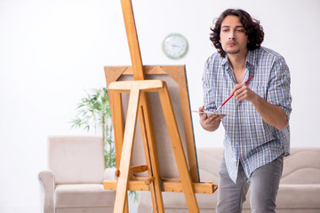 Young handsome man enjoying painting at home