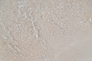 Top view of sea water on the clean white sand from wave ripple