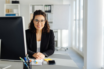 Young businesswoman sitting in an office - obrazy, fototapety, plakaty