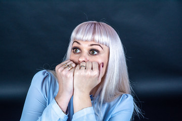 Portrait of a woman on a black background. The woman is blonde, dressed in a light blouse. Shows various postures expressing emotions.