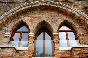 Modern Venetian-style houses with three-light Gothic windows. Brick wall characteristic of the houses of Venice, Italy.