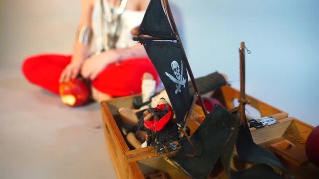 A child in a pirate costume sits near a set of pirate toys in a kindergarten.