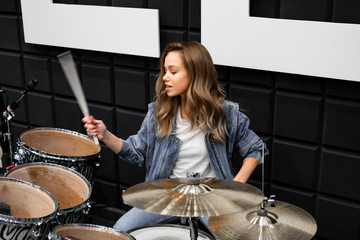 Creativity and music. Young beautiful girl plays the drums. Recording Studio. Musical equipment.