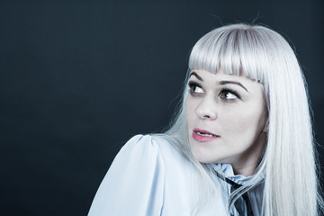 Portrait of a woman on a black background. The woman is blonde, dressed in a light blouse. Shows...