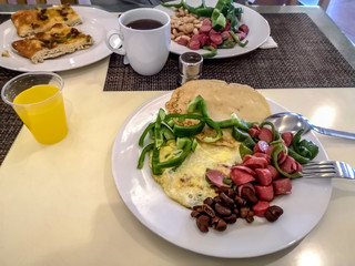 Unhealthy high-calorie breakfast at the Sharm El Sheikh Hotel (Egypt). Beans, sausages, pancake, omelette and green pepper with carbonated drink in a plastic glass