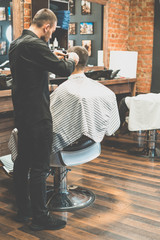 Haircut at the hairdresser. Barber cuts the hair on the client's head. The process of creating...