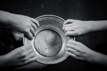 Two pairs of children's hands hold a metal plate.
