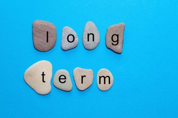 The word long term is written on polished natural stones that are true to color. The words are...