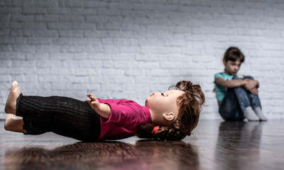 Shooting in the Studio. There's a doll on the floor. A girl is sitting against the wall.