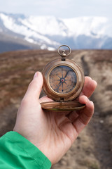 Man with retro compass in hand in high mountains. Travel concept. Landscape photography