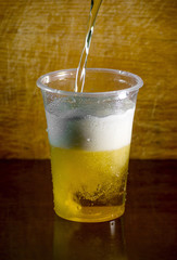 bartender pouring a large lager beer in tap. Pouring fresh beer for client. Wood in the background
