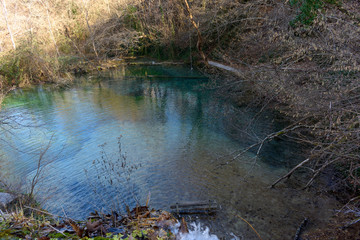 Waterfalls with a wooden bench in the lake. The Emerald ( Smaragdenia ) Lake at Skra in Greece.