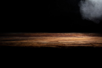 table top made of old wood with a spot of light and blue smoke in dark colors