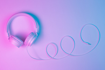 Retro 90s style photo of white stylish wireless headphone in neon lights. Music concept.