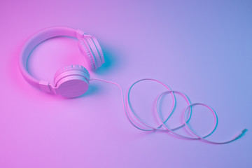 Retro 90s style photo of white stylish wireless headphone in neon lights. Music concept.
