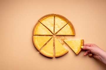 Cheesecake on a cream-colored background. Woman hand  taking a piece of the pie