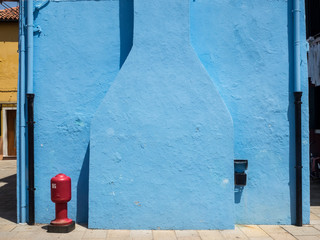 Detalle de una fachada azul con toma de agua roja en Burano