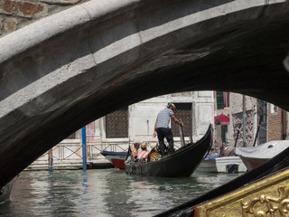 Fototapeta na wymiar Góndola con turistas pasando bajo uno de los puentes de Venecia
