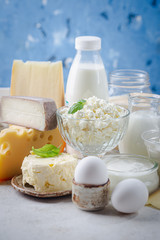 Fresh dairy products, milk, cottage cheese, eggs, yogurt, sour cream and butter on blue background