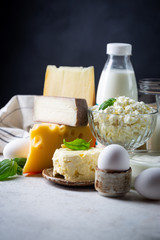 Fresh dairy products, milk, cottage cheese, eggs, yogurt, sour cream and butter on white table, black background