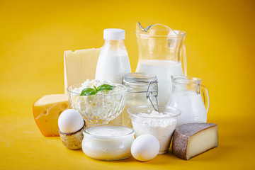 Fresh dairy products, milk, cottage cheese, eggs, yogurt, sour cream and butter on yellow background