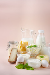 Fresh dairy products, milk, cottage cheese, eggs, yogurt, sour cream and butter on pink background