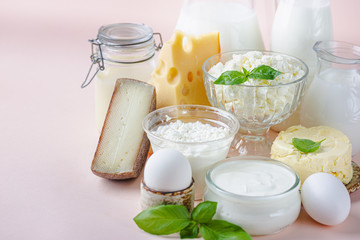 Fresh dairy products, milk, cottage cheese, eggs, yogurt, sour cream and butter on pink background