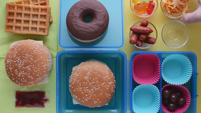woman puts unhealthy food in a lunch box, top view