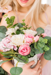 close-up of women's hands holding a bouquet of flowers in soft pink tones. Gift box with a bouquet for women's day and Valentine's Day.