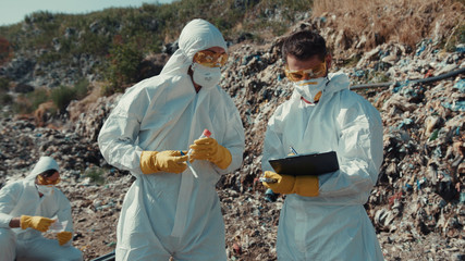 Ecology team working on landfill site collecting toxic garbage and estimating pollution. Close-up...