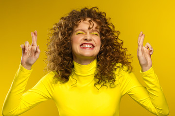 Young beautiful smiling women with curly hair and crossing fingers and wishing good luck. Funny...