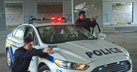 AMSTERDAM, NETHERLANDS - 19 AUGUST, 2019: Two police officers getting out of patrol car with flashing lights pointing handguns on thives controlling the robbery scene on city street. Police on duty. © Fractal Pictures