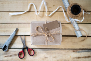 handmade gift box tie a twine bow, a tool for its manufacture on a wooden background, top view, copy space