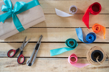 handmade gift box tie a green bow, a tool for its manufacture on a wooden background, top view, copy space